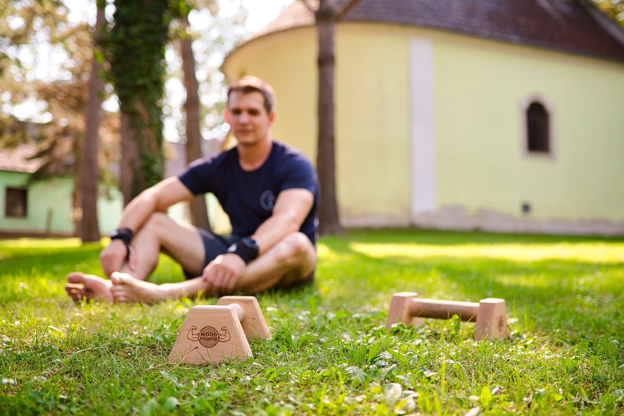 Christoph sitzt im Gras mit Parallettes vor ihm