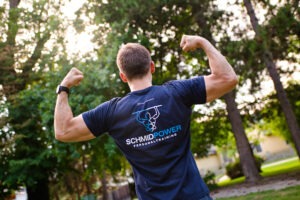 Christoph von hinten mit Logo am Shirt und geflexten Armen