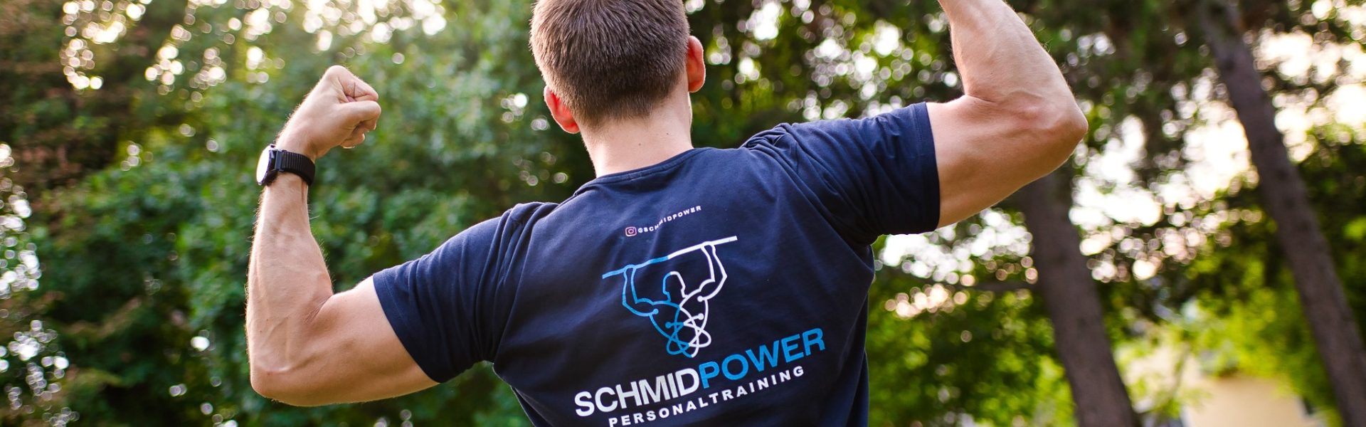 Christoph von hinten mit Logo am Shirt und geflexten Armen